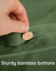 Hand pressing a wooden button on a green fabric with text 'Sturdy bamboo buttons'.