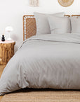 Neatly made bed with gray bedding in a bedroom setting.
