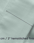 Close-up of light green fabric with a hemstitched finish and measurement text.