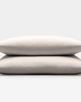 Two beige sand pillows stacked on a light gray background
