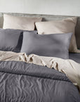 Gray bedding set with pillows on a bed against a white wall