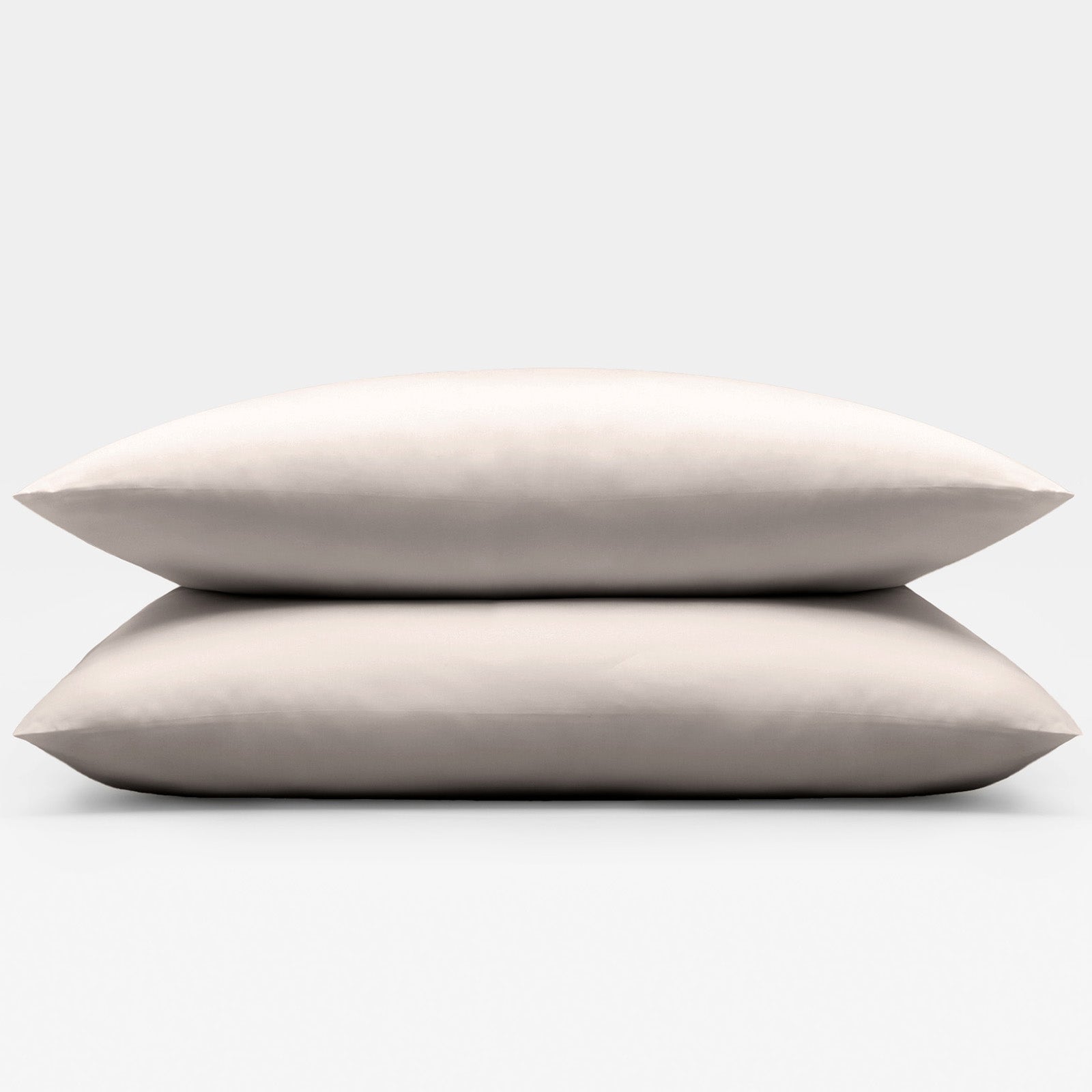 Two beige sand pillows stacked on a light gray background