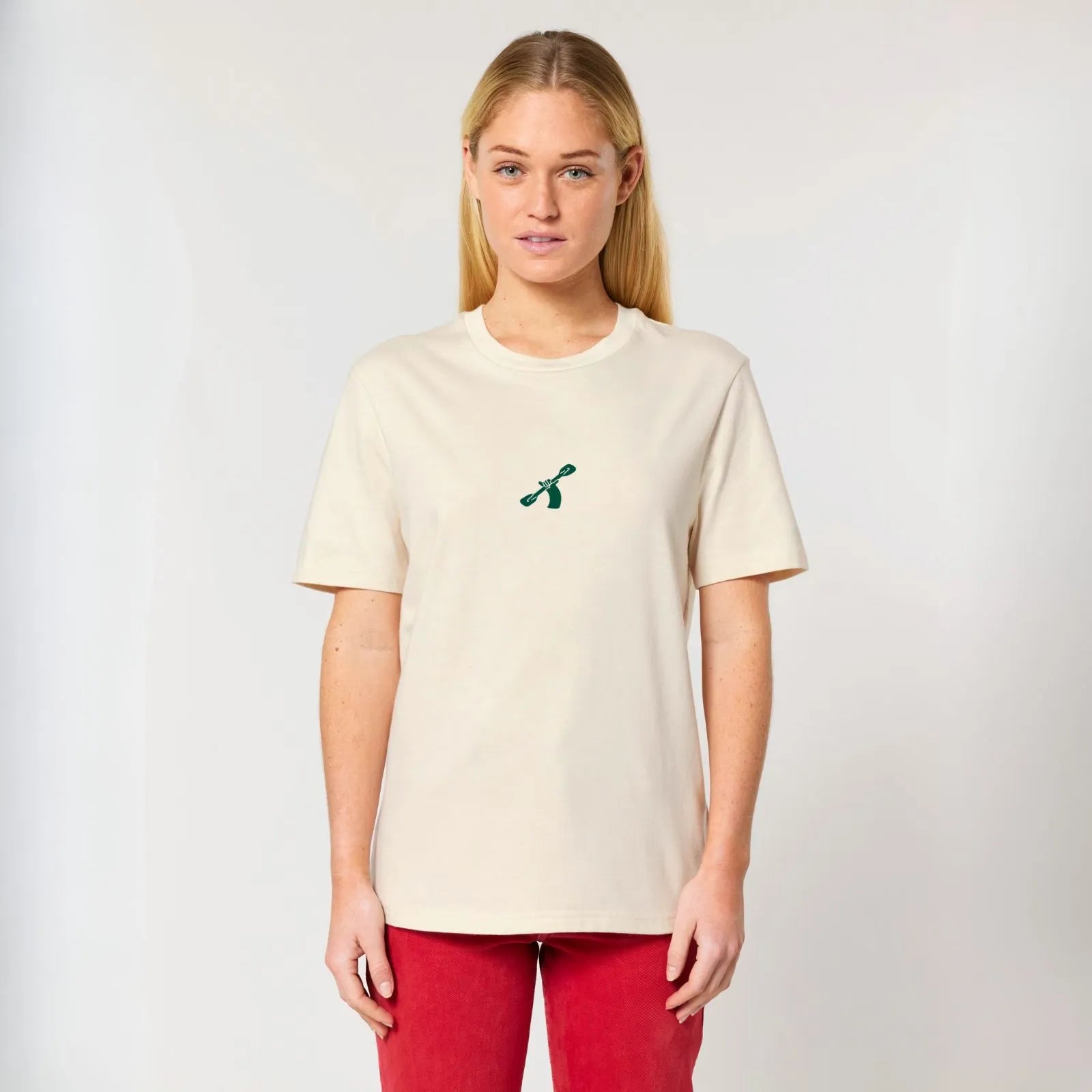 A woman wearing a City to Ocean T-shirt with 'City to Ocean' logo design on the front. 100% Cotton in natural raw white, untreated sustainable fabric on plain background
