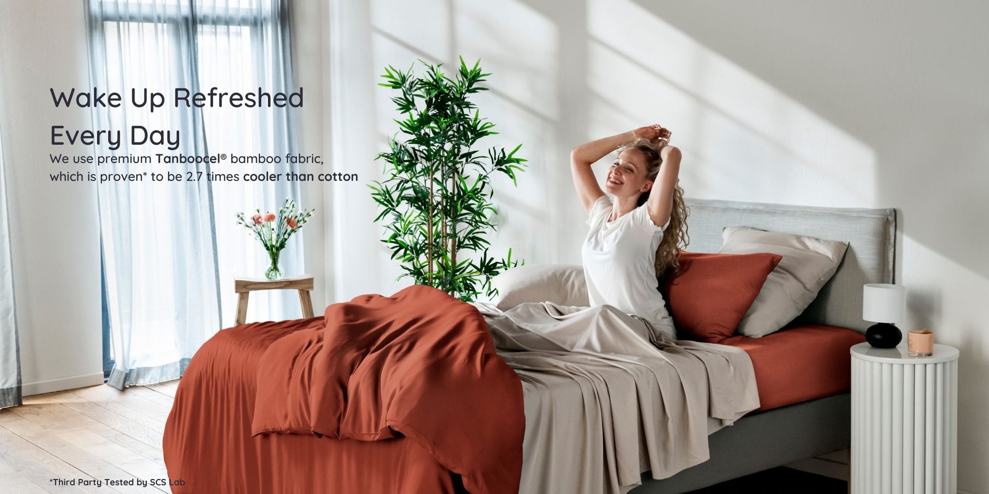 Woman waking up in a bright bedroom with bambaw cozy terracotta bamboo bedding and white walls.